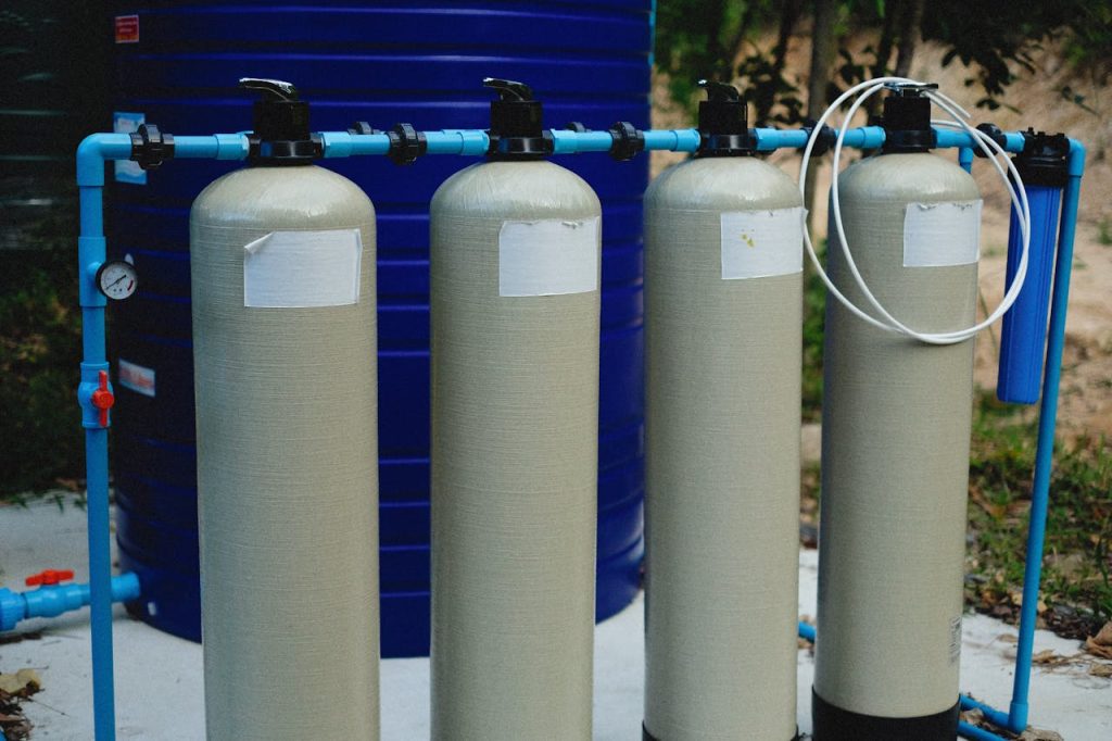 pexels-photo-12726229 Four beige tanks in an outdoor water treatment setup with blue piping.